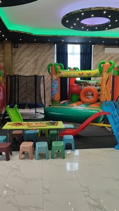 Postavka pokretne igraonice Baloo u sali — dvorac na naduvavanje, trampolina i dečji stočići sa stolicama
