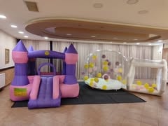 Ljubičasto-roze dvorac na naduvavanje i prozirna kupola sa žutim balonima u sali